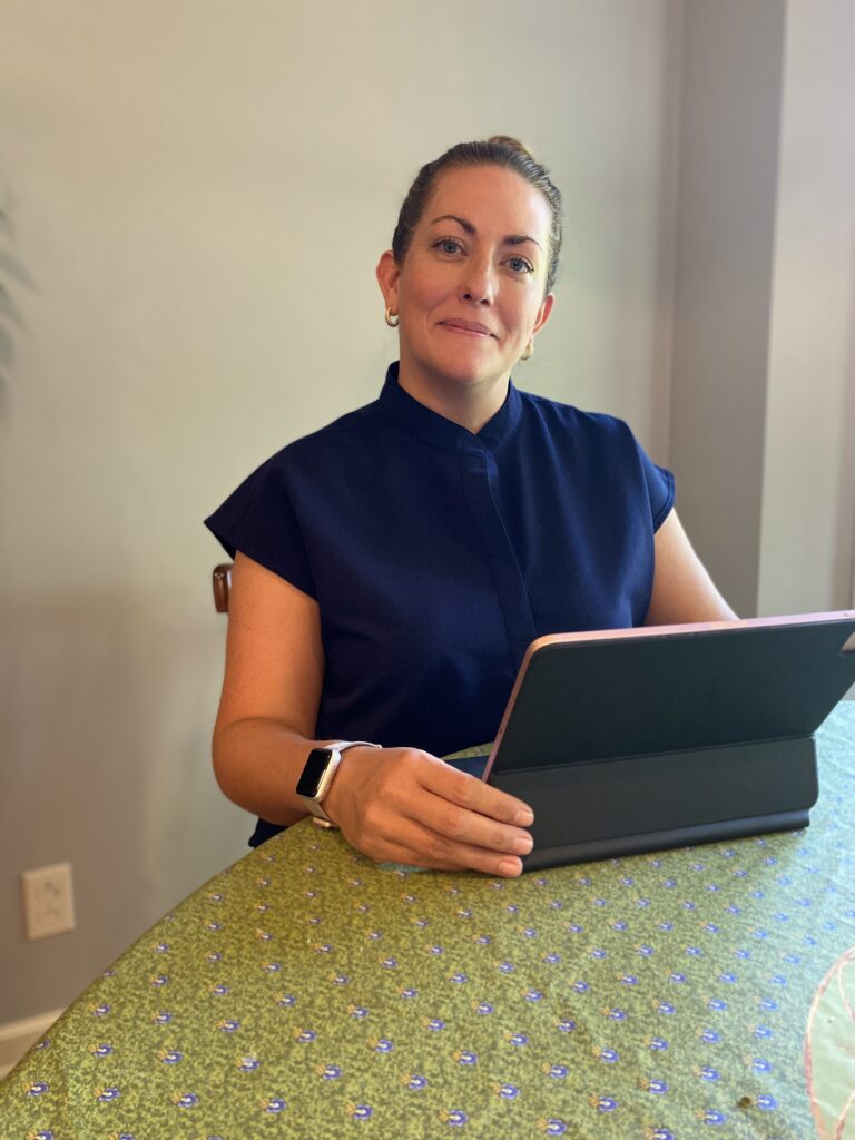 Working parent, Heather, sitting at her iPad at the kitchen table